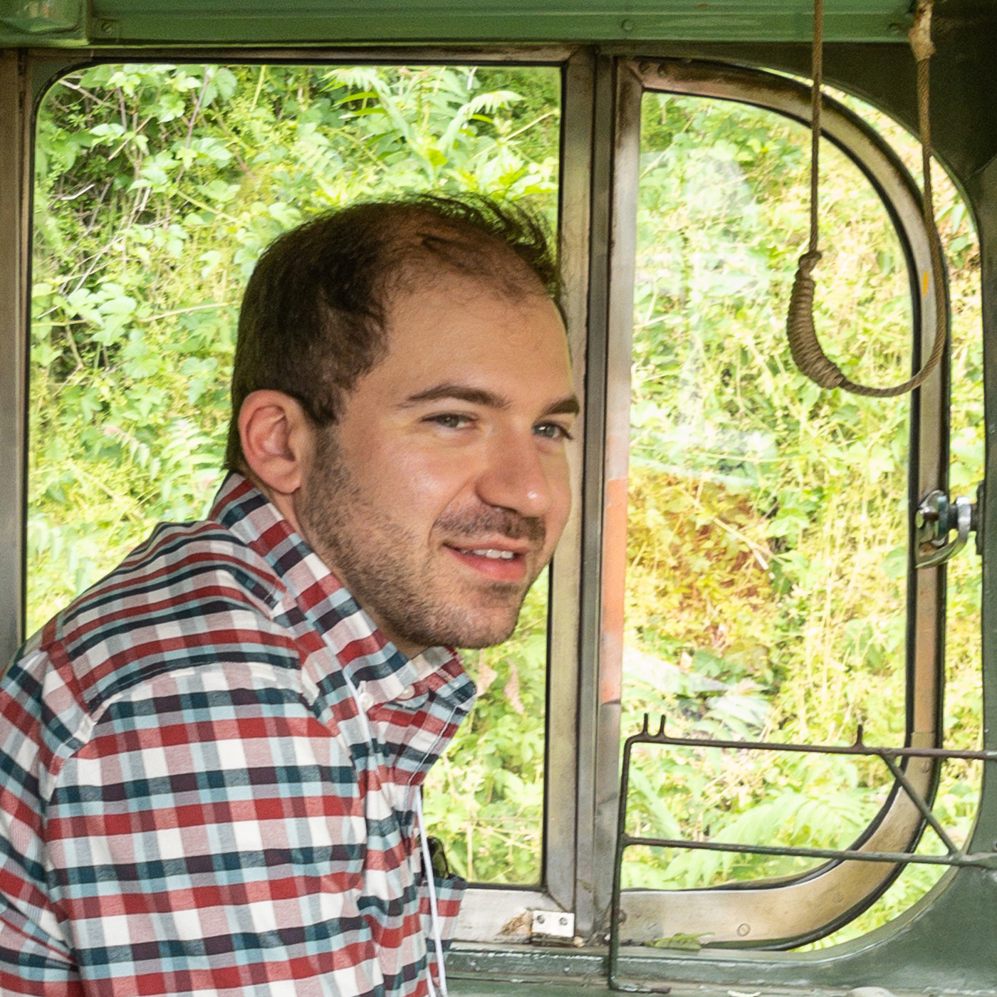 Photo of Doug, a white man in his 30s with short brown hair and brown stubble, in the operator's seat of a vintage PCC streetcar